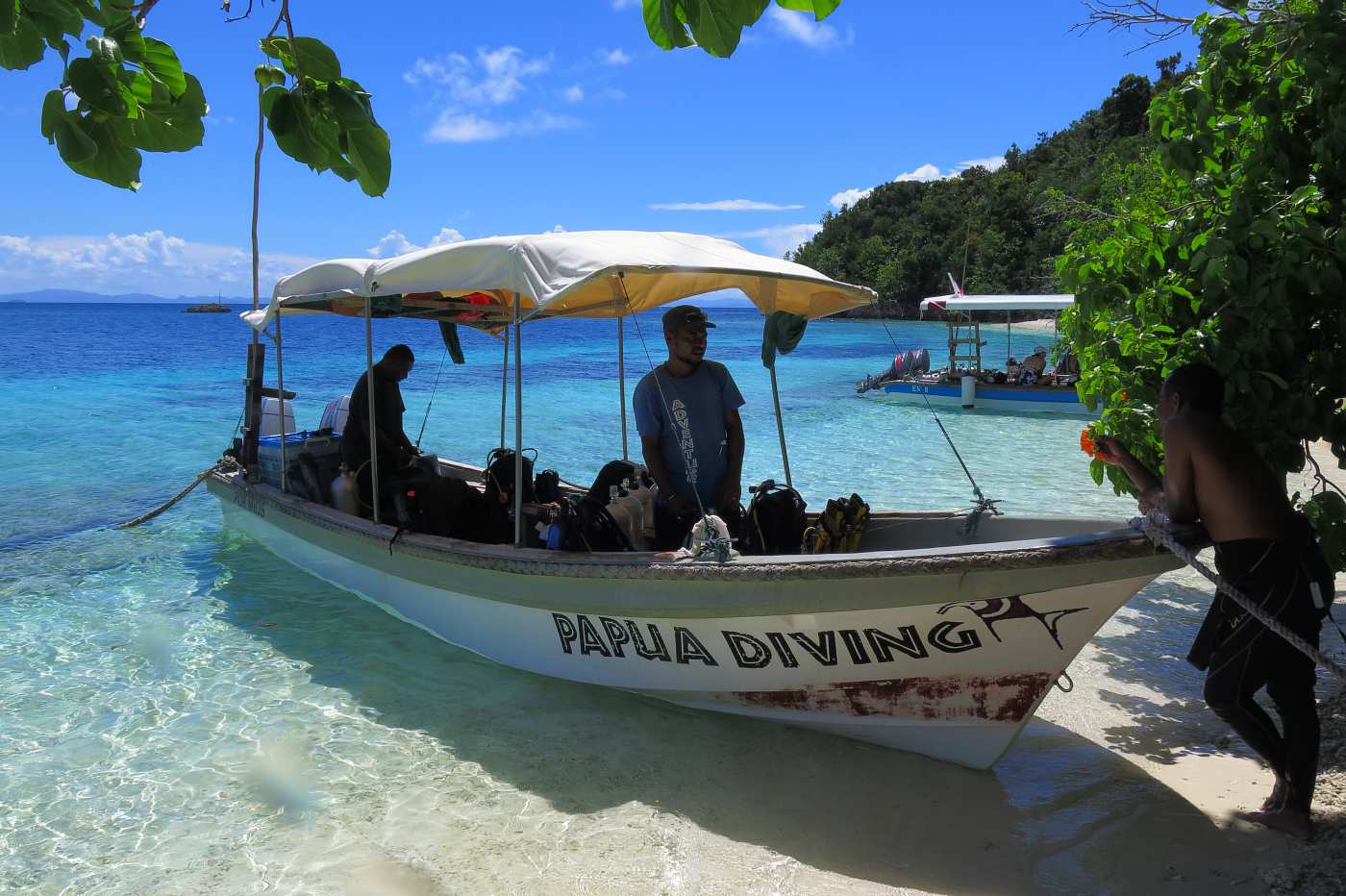 Fantastické tropické pobřeží u dalšího z mnoha nádherných ostrovů, posádka potápěčského člunu přehazuje láhve.